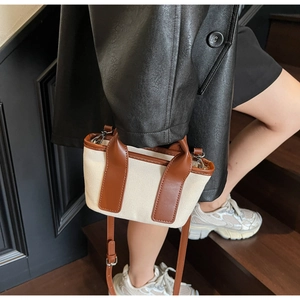 Detail of canvas tote with brown leather handles on dark wooden stairs