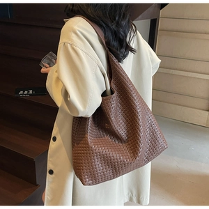 Detail of dark brown woven tote bag paired with a beige trench coat for elegant daily wear