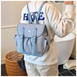 Detailed view of the light blue backpack with canvas texture and heart flower embroidery