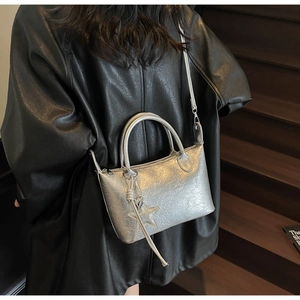 Dettaglio della borsa argento metallizzato con ciondolo a stella e trama sul modello