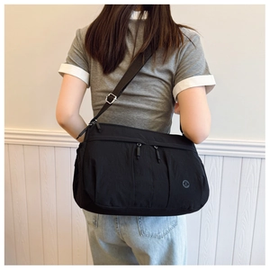 Rear view of black nylon crossbody bag with adjustable wide strap on model back