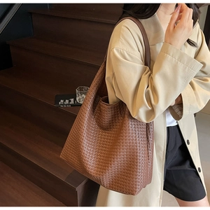 Close-up of dark coffee woven tote bag texture and integrated shoulder strap detail