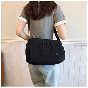Close-up of black crossbody bag featuring dual front zippers and adjustable wide strap