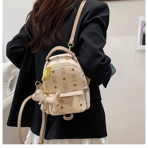 Detail of cream mini backpack with teddy bear print and hanging dog charm accessory