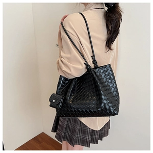 Detail view of large black woven tote bag with knotted straps and hanging mini pouch