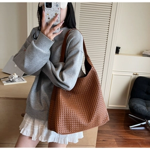 Brown woven shoulder bag with large capacity shown in a stylish professional setting