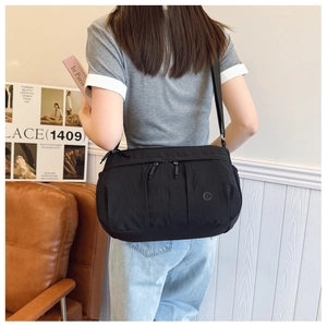 Detail of a black nylon square crossbody bag worn by a model in a minimalist setting