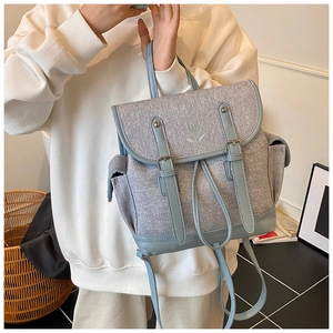 Detail of tulip embroidery and magnetic buckle on light blue woven backpack