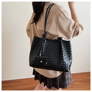 Detail of black woven leather tote bag with small coin purse shown on a model