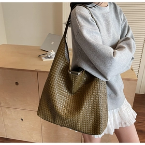 Detail of hand-woven deep olive green leather tote bag in a minimalist home setting