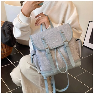 Detail of tweed travel backpack with floral embroidery and leather buckle straps