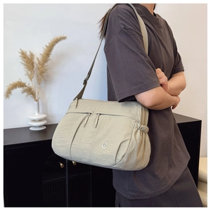 Detail view of khaki waterproof nylon crossbody bag with multi-zipper pockets and wide strap