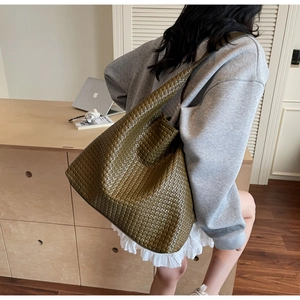 Close-up of olive green woven leather tote bag shoulder carry showing texture and large capacity