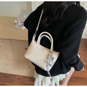 Elegante borsa a mano in pelle crema con ciondoli a stella e cuore in un contesto reale