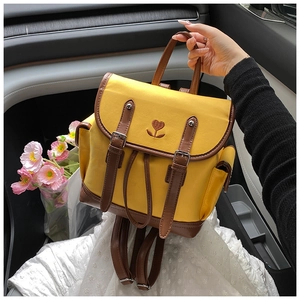 Close-up of yellow backpack featuring floral heart embroidery and brown leather straps