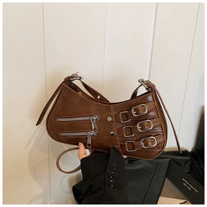 Close-up of brown pleated leather bag featuring punk style metal zippers and buckles