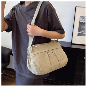 Detail view of large beige nylon crossbody bag with multi-pockets and adjustable strap