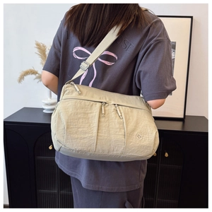 Close-up of beige nylon crossbody bag with multi-pocket design and adjustable strap