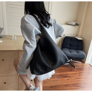 Detailed view of a black woven leather tote bag shown from a side-back angle