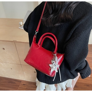 Dettaglio di una borsa a tracolla rossa lucida con ciondoli a stella su una modella