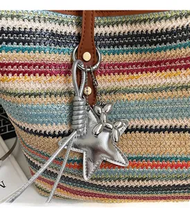 Nahaufnahme der gewebten Boho-Tasche mit dekorativen Stern- und Ballonhund-Anhängern