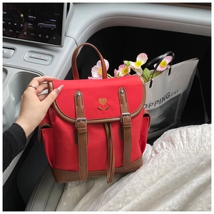 Detail of red canvas backpack with floral heart embroidery and brown leather trim