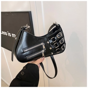 Close-up of black punk shoulder bag with silver double zippers and metal studs detail