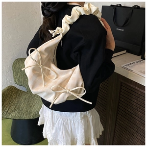 Detail der cremefarbenen Karo-Tasche mit Schleifen und plissiertem Schultergurt