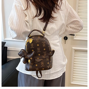 Detailed shot of dark brown mini backpack with bear print and cute dog charm accessory