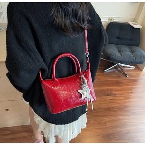 Borsa rossa in pelle verniciata con ciondolo a stella indossata da modella in ambiente casa