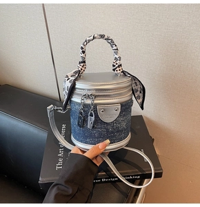 Détail du sac seau en denim bleu avec bordure en cuir argenté et poignée en foulard de soie