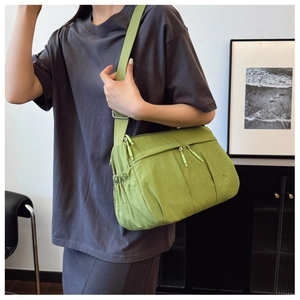 Detail of green nylon crossbody bag showing multiple zip pockets and adjustable strap