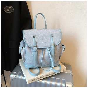 Detail of light blue tweed and leather backpack with floral embroidery and buckle straps