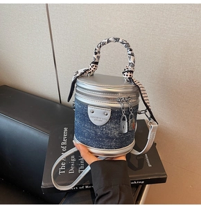 Détail du sac seau en denim avec bordure argentée, cadenas et poignée en foulard