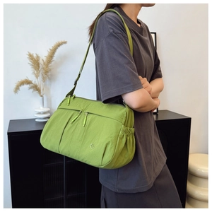 Green high-capacity nylon shoulder bag with multi-pocket design on a person