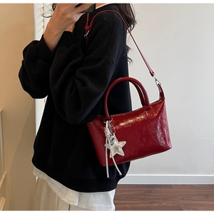 Borsa a mano rossa in vernice con ciondolo a stella mostrata in stile a tracolla