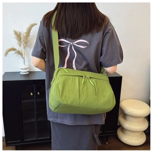 Detail of green nylon crossbody bag showing crinkled texture and wide shoulder strap