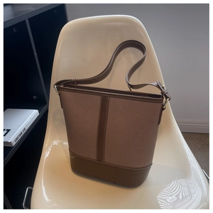 Detail einer Vintage-Eimertasche aus Canvas und braunem Leder auf einem weißen Stuhl