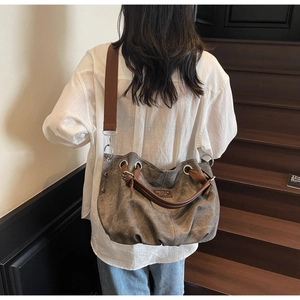 Detail of taupe washed canvas tote bag with leather straps and metal eyelet accents