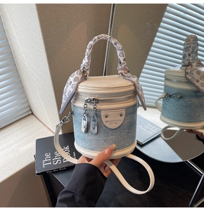 Détail du sac seau en jean bleu avec strass, poignée blanche et foulard en soie à coeurs