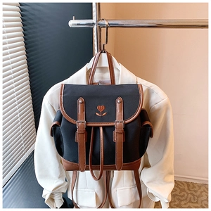 Detailed close-up of vintage backpack with floral embroidery and brown leather buckle straps