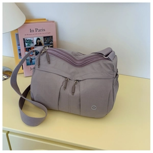 Detail of mauve nylon crossbody bag with multi-zipper pockets and adjustable wide strap