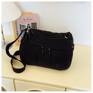 Detail view of multi-compartment black nylon crossbody bag with adjustable wide strap