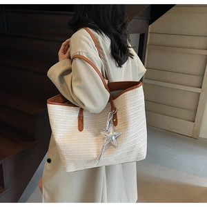 Detail der Boho-Stroh-Tote-Tasche mit silbernem Sternanhänger und braunen Lederriemen
