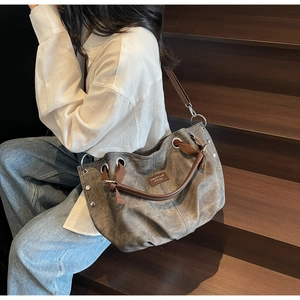 Detail of vintage grey tote bag showing textured fabric, brown leather straps, and metal rivets