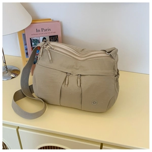 Detailed view of Khaki nylon crossbody bag with multiple zippers and adjustable strap