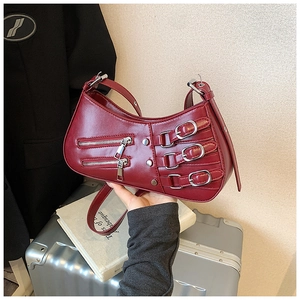 Detail of burgundy leather shoulder bag with metallic buckles and punk zippers