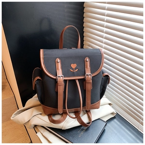 Detailed embroidery of heart flower on black canvas backpack with brown leather trim