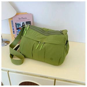 Detail view of grass green nylon crossbody bag with multiple zippers and wide strap