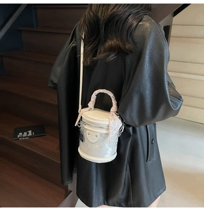 Modèle portant un mini sac seau blanc avec foulard à cœurs sur escalier en bois
